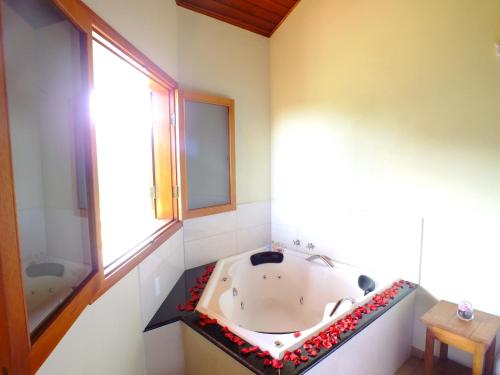 a bathroom with a bath tub and a window at Pousada Vista da Serra Monte Verde in Monte Verde