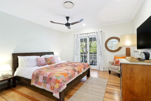 a white bedroom with a bed and a kitchen at The Odd Gecko B&B in Canungra