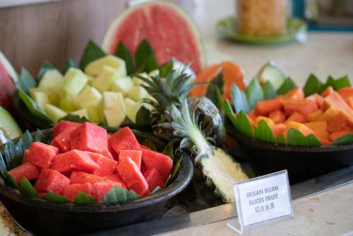 a bunch of fruits in bowls on a counter at Grand Livio Kuta Hotel in Legian