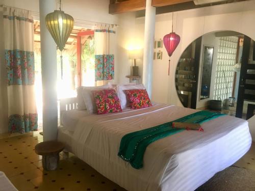 a bedroom with a large white bed with colorful pillows at Le Domaine De Tam Hai Resort in An Hòa