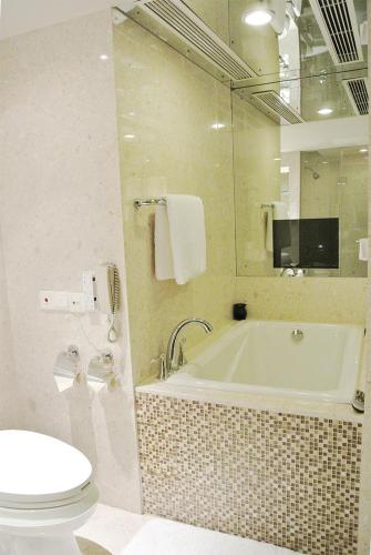 a bathroom with a tub and a toilet and a sink at Kunming Haitian Hotel in Kunming