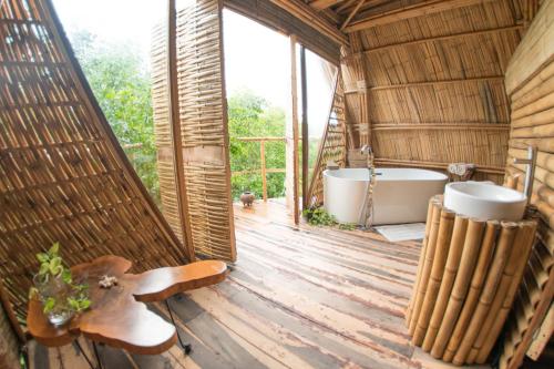 a bathroom with a tub and a toilet in a hut at Mamasan Treehouses & Cabins in Tulum