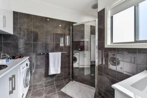 a bathroom with a shower and a washing machine at Plovers Rest at Cape Douglas in Cape Douglas