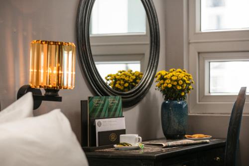 a table with a mirror and a vase with yellow flowers at Shining Central Hotel & Spa in Hanoi