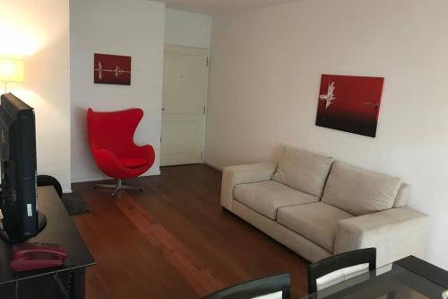 sala de estar con sofá y silla roja en Best Location at PUERTO MADERO!! Parking, Gym, pool (1bed, 1 bath) en Buenos Aires