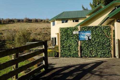 a sign in front of a fence next to a house at Hunters Moon in Mosgiel