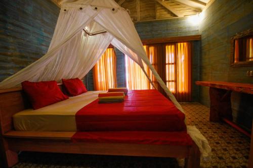 a bedroom with a bed with a mosquito net at Segar Village in Gili Air