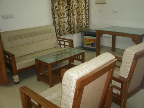a living room with a couch and a table and chairs at Jacaranda Holiday Home in Cochin