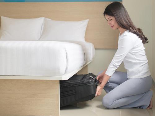 a woman kneeling next to a bed with a suitcase at HOP INN Phuket Old Town in Phuket Town