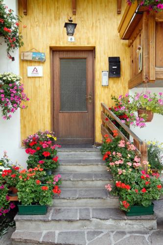 a wooden door with flowers in front of a house at Appartamenti Lezuo Iris in Arabba