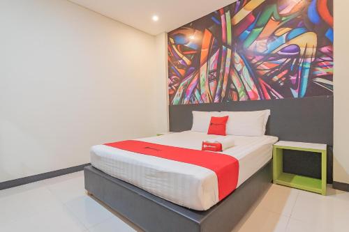 a bedroom with a bed with a painting on the wall at RedDoorz at Rajawali KM 5 Palangkaraya in Palangkaraya