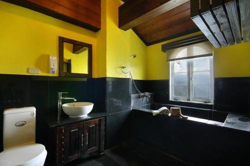 a bathroom with yellow and black walls and a sink at Provence Rose Lodge in Renai