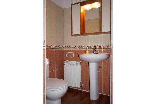 Un baño con inodoro, lavabo y espejo. en Casa Rural Os Arregueses, en Alquézar