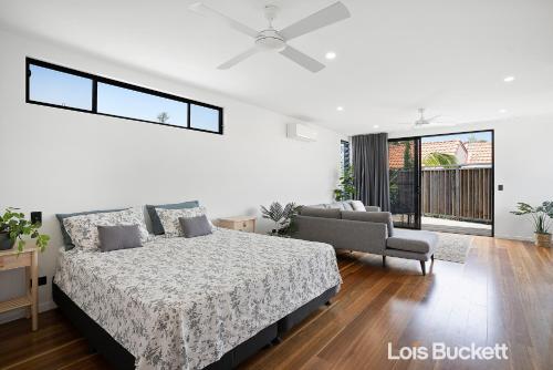 um quarto branco com uma cama e um sofá em Grottamare em Lennox Head