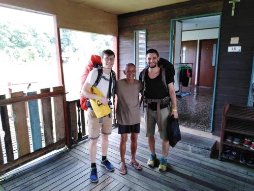 a group of three men standing on a porch at AA Homestay in Mulu