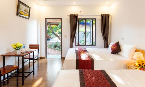 ein Hotelzimmer mit 2 Betten, einem Tisch und einem Fenster in der Unterkunft Nam Nhung Tam Coc Homestay in Ninh Bình