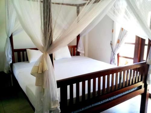 a bedroom with two beds with a canopy at Ceylon Surf Guest and Restaurant in Weligama
