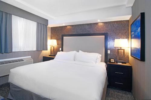 a hotel room with a large white bed and a window at Holiday Inn Express and Suites Calgary by IHG in Calgary