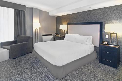 a bedroom with a large white bed and a chair at Holiday Inn Express and Suites Calgary by IHG in Calgary