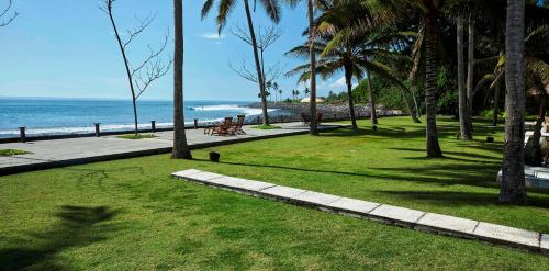 a park with palm trees and a beach with the ocean at Villa Mandala in Jasri