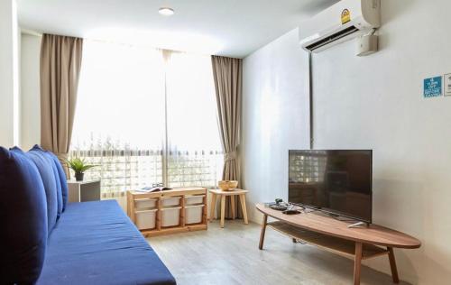 a living room with a blue couch and a large tv at Vann House Hua Hin in Hua Hin