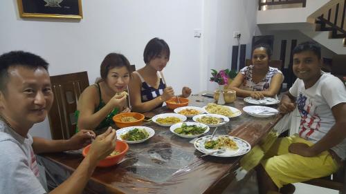 a group of people sitting around a table eating food at COCO Rooms in Galle