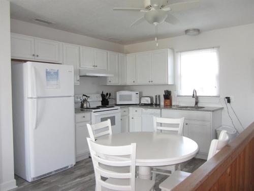 - une cuisine blanche avec une table et un réfrigérateur blanc dans l'établissement 40310 A Due East Lane Duplex Townhouse, à Avon