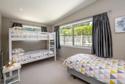 a bedroom with two bunk beds and a window at Wind Down on Esther in Martinborough 