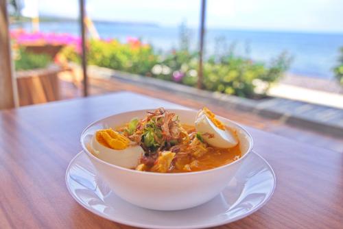 a bowl of soup on a table with a view of the ocean at Seamount Hotel Amed in Amed