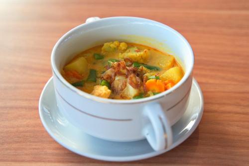 a cup of soup on a plate on a table at Seamount Hotel Amed in Amed