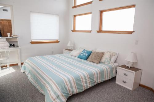 a white bedroom with a bed and two windows at THE SUNNY SPOT cottage in Frisco