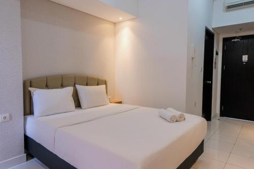 ein Schlafzimmer mit einem weißen Bett und einem Handtuch darauf in der Unterkunft Minimalist Studio Apartment at Casa De Parco By Travelio in Samporo