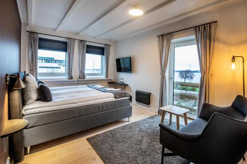 a bedroom with a bed and a chair and windows at Hotel Sidesporet in Holbæk