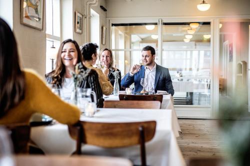 a group of people sitting at a table in a restaurant at Hotel Sidesporet in Holbæk