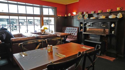 a restaurant with tables and chairs and a fireplace at Law Courts Hotel in Dunedin