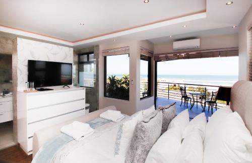1 dormitorio con cama blanca y vistas al océano en C' la Vie Luxury Accommodation en Melkbosstrand