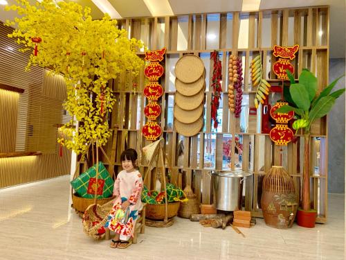 a little girl is sitting in a room with baskets at Adora Hotel in Ho Chi Minh City