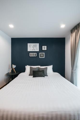 a bedroom with a large white bed with a blue wall at Nimman Villa 17 Chiangmai - SHA PLUS in Chiang Mai