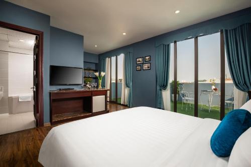 - une chambre avec un grand lit blanc et une télévision dans l'établissement Serene Boutique Hotel & Spa, à Hanoï