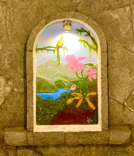 a window in a stone wall with a painting of a bird at Hotel Boutique TEKALI INN in Cuetzalán del Progreso