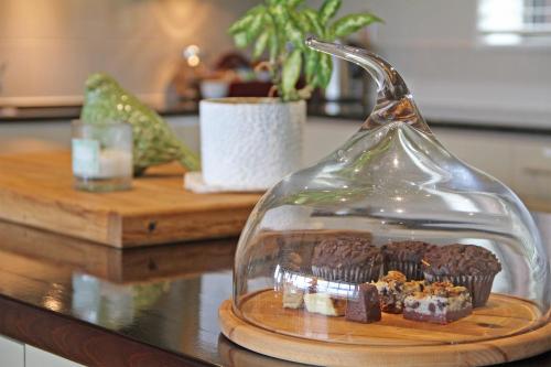 a plate of chocolate muffins in a glass dome on a counter at Amuri Estate Luxury Lodge in Hanmer Springs
