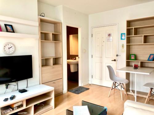 a living room with a television and a table and a chair at 1BR Condo 5 Min to BTS 1000Mbps Fiber Wi-Fi great location in Bangkok