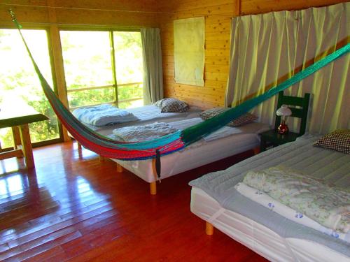 two beds in a room with a hammock at 屋久島コテージ対流山荘 in Yakushima