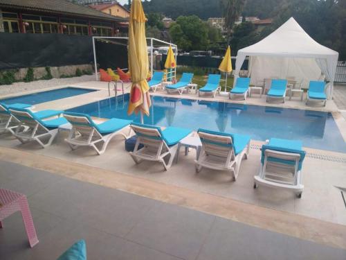 een zwembad met stoelen en parasols en een aantal artikelen bij Paddys Apartments, Hisarönü in Fethiye