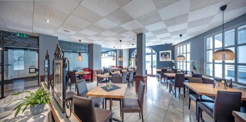 ein Restaurant mit Tischen, Stühlen und Fenstern in der Unterkunft HotelChur.ch in Chur