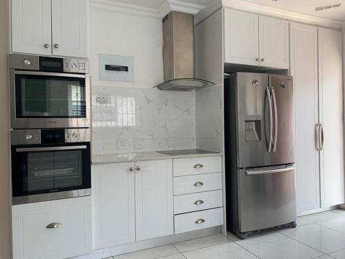 a kitchen with white cabinets and a stainless steel refrigerator at White House lodge in Scotburgh in Scottburgh