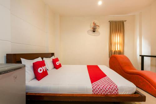 a bedroom with a bed with red pillows and a chair at Aqua Hoa My Hotel in Ho Chi Minh City