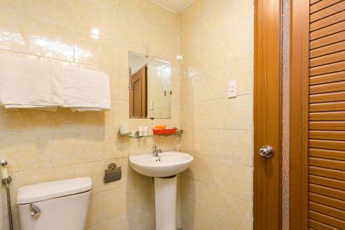 een badkamer met een wastafel, een toilet en een spiegel bij Aqua Hoa My Hotel in Ho Chi Minh-stad