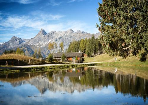 a lake with a house and mountains in the background at TUI BLUE Montafon in Schruns-Tschagguns