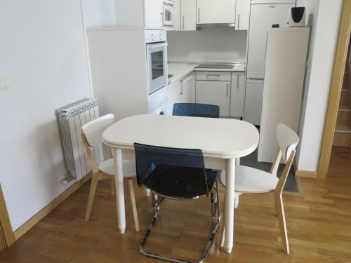 a white kitchen with a white table and chairs at Tudela balcón de Bardenas in Tudela